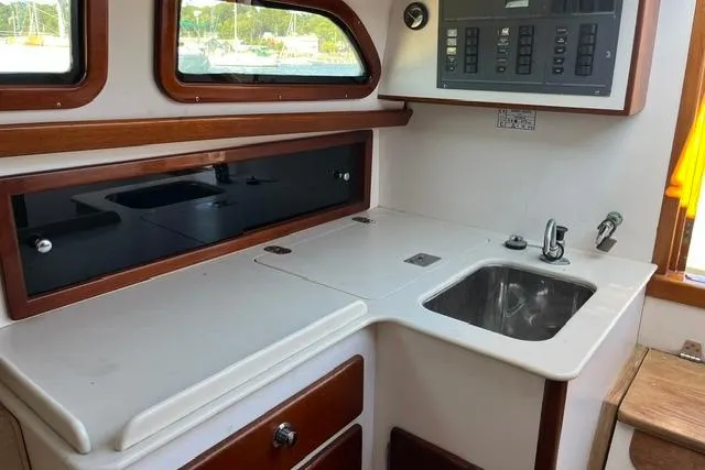 Slide: The Image of Compact kitchen area in a 2006 Morris 36 boat, featuring a sink and storage cabinets. - 29