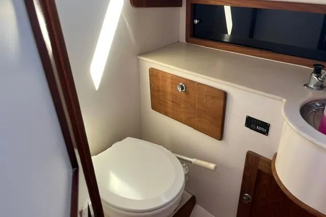 Slide: The Image of Compact bathroom in a 2006 Morris 36 boat, featuring a toilet and wooden cabinetry. - 31