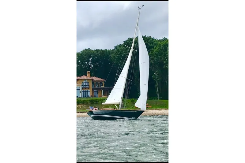 Slide: The Image of Sailing yacht Morris 36 (2006) on water near a coastal house with lush greenery. - 6