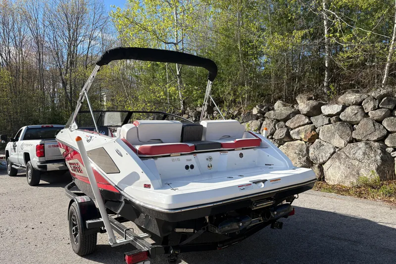 Slide: The Image of 2023 Scarab 215 ID boat on trailer, parked near a forested area. - 3