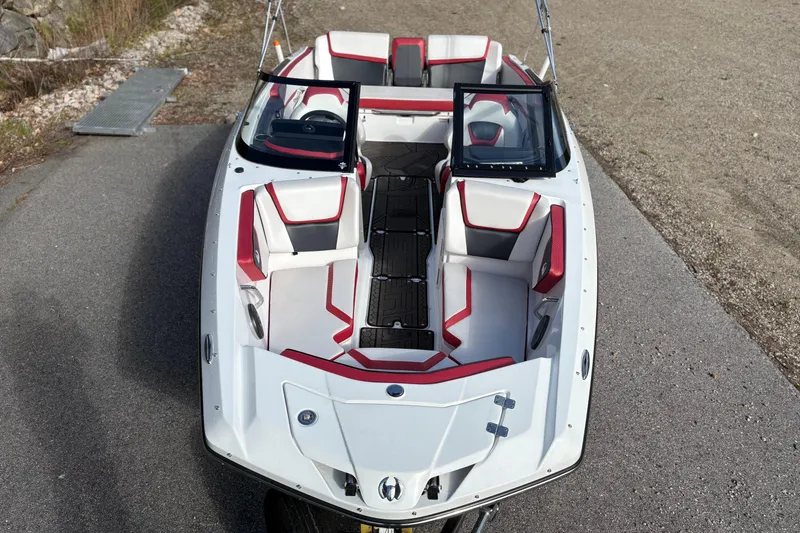 Slide: The Image of 2023 Scarab 215 ID boat with red and white interior, parked on pavement. - 8