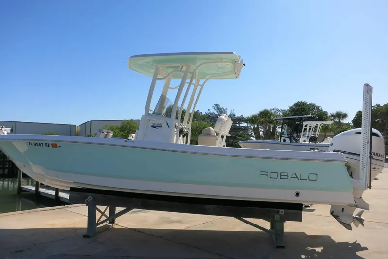 Slide: The Image of 2018 Robalo 246 Cayman boat on display, light blue hull, parked on a trailer. - 4