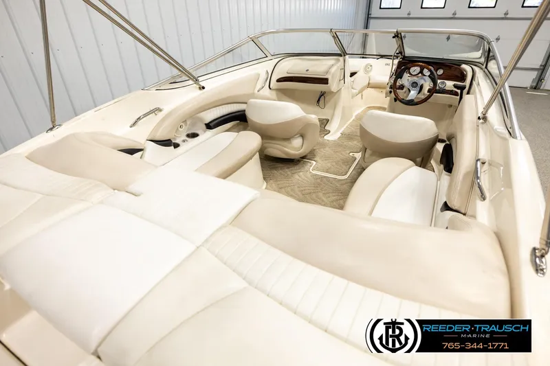Slide: The Image of 2007 Glastron GXL 205 boat interior with beige seating and steering wheel in a showroom. - 12