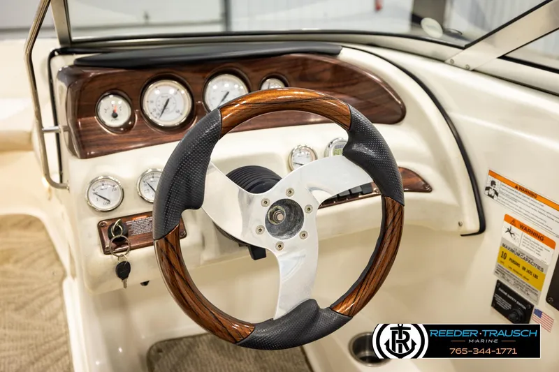 Slide: The Image of 2007 Glastron GXL 205 boat dashboard with wood-accented steering wheel and gauges. - 34