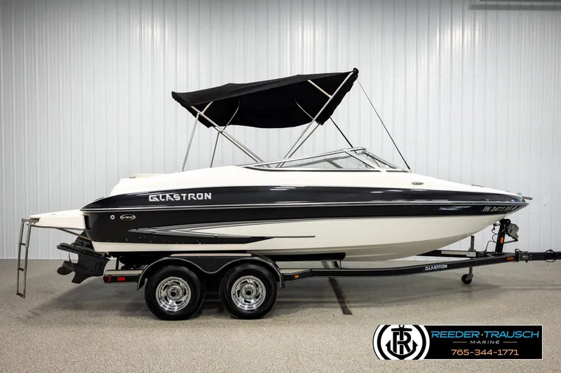 Slide: The Image of 2007 Glastron GXL 205 boat with black canopy on a trailer in a showroom. - 5