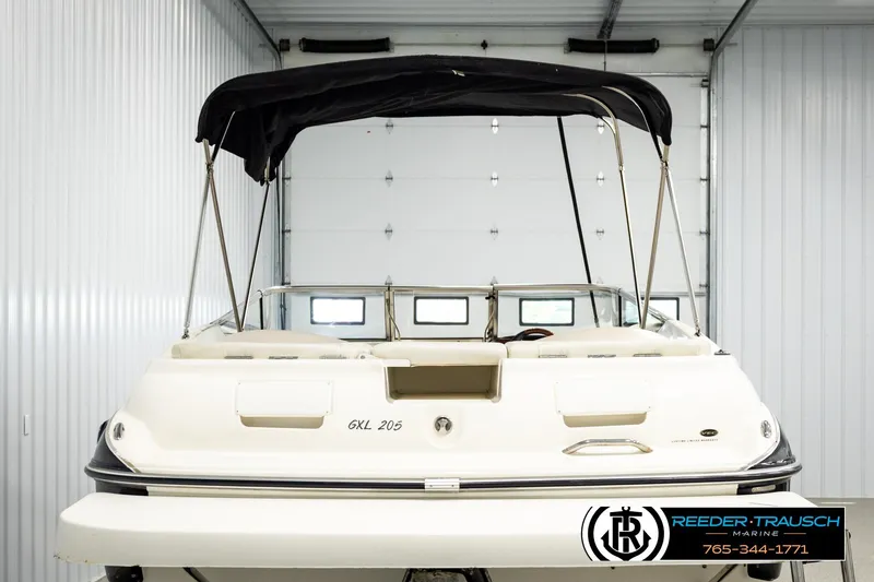 Slide: The Image of 2007 Glastron GXL 205 boat in storage, featuring a black canopy and white exterior. - 7