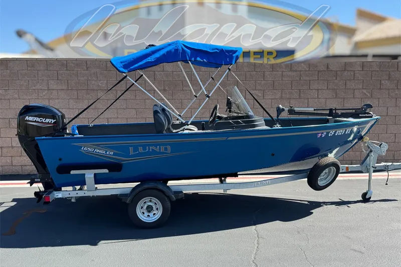 The Image of 2025 Lund 1650 Angler SS boat with blue canopy on trailer, featuring Mercury outboard motor. - 0