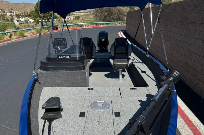 Slide: The Image of 2025 Lund 1650 Angler SS boat with canopy, seats, and fishing equipment on a paved road. - 8