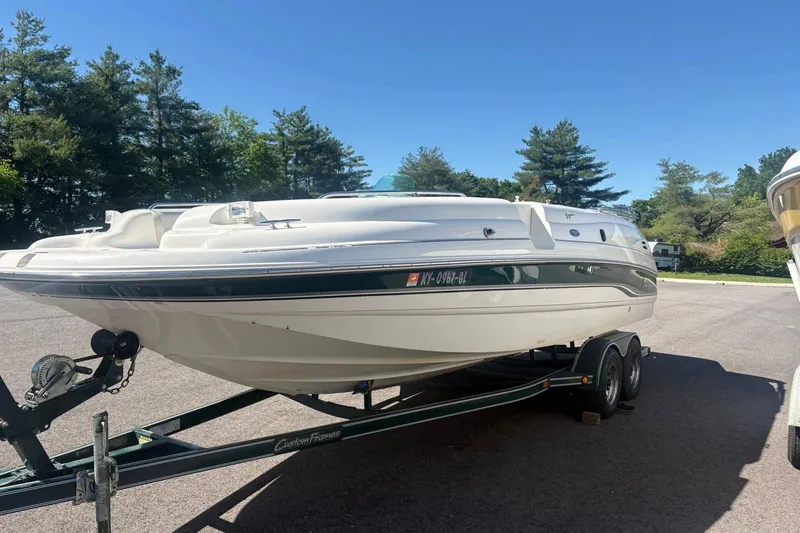 The Image of 2000 Chaparral Sunesta 232 boat on trailer, parked outdoors under clear blue sky. - 0
