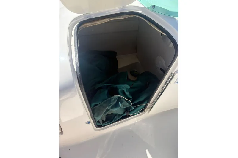 Slide: The Image of Open storage compartment on a 2000 Chaparral Sunesta 232 boat, containing green fabric. - 10
