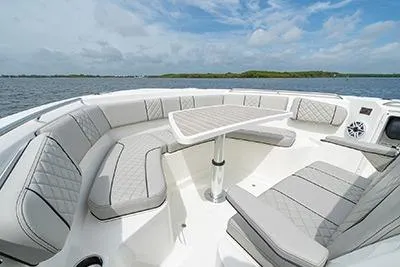 Slide: The Image of 2026 Pursuit S 358 Sport boat interior with spacious seating and table, under a clear sky. - 17