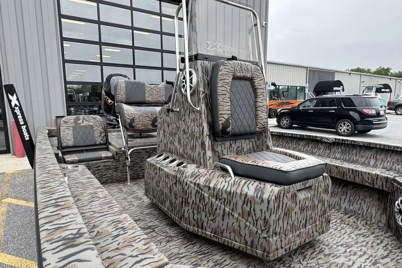 Slide: The Image of 2026 Xpress H22B Bay boat with camouflage interior, parked outside dealership. - 11
