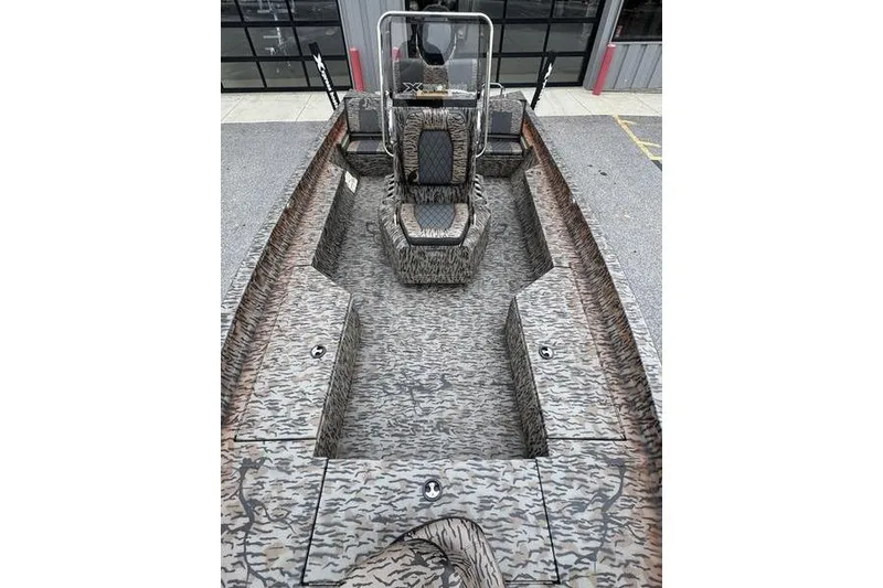 Slide: The Image of 2026 Xpress H22B Bay boat with camouflage interior, parked outside a building. - 12