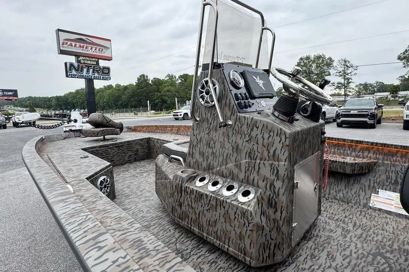 Slide: The Image of 2026 Xpress H22B Bay boat with camouflage design, parked outdoors near dealership. - 6