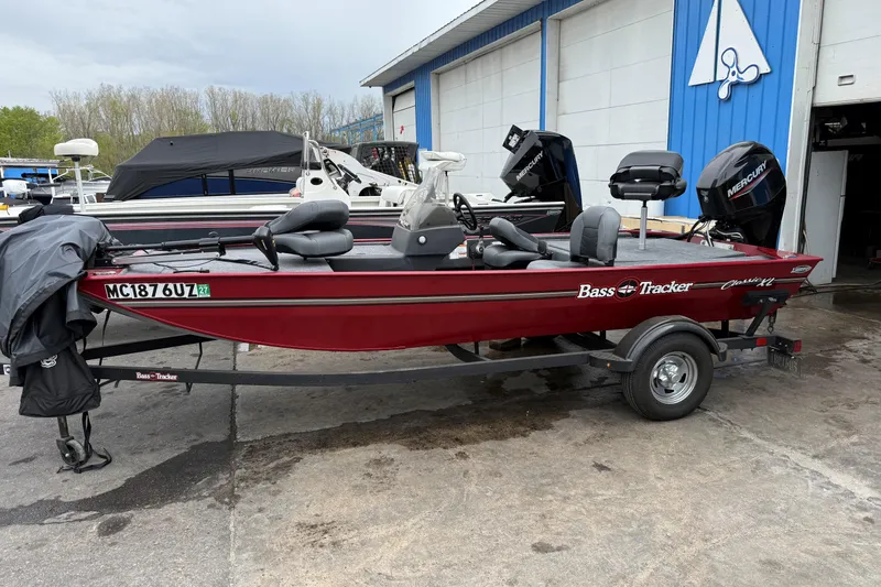 The Image of 2024 Tracker Bass Tracker Classic XL boat on trailer, parked outside a blue and white building. - 1