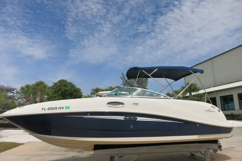 The Image of 2008 Sea Ray 260 Sundeck boat with blue hull and canopy, parked outdoors. - 0
