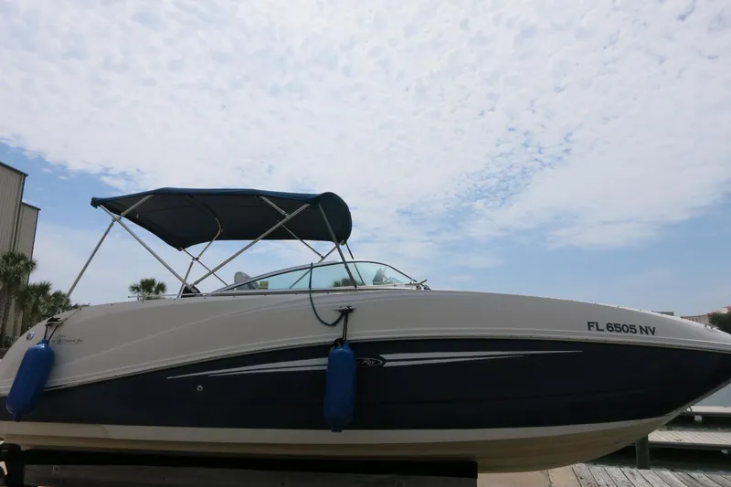 Slide: The Image of 2008 Sea Ray 260 Sundeck boat with blue canopy docked under a cloudy sky. - 3