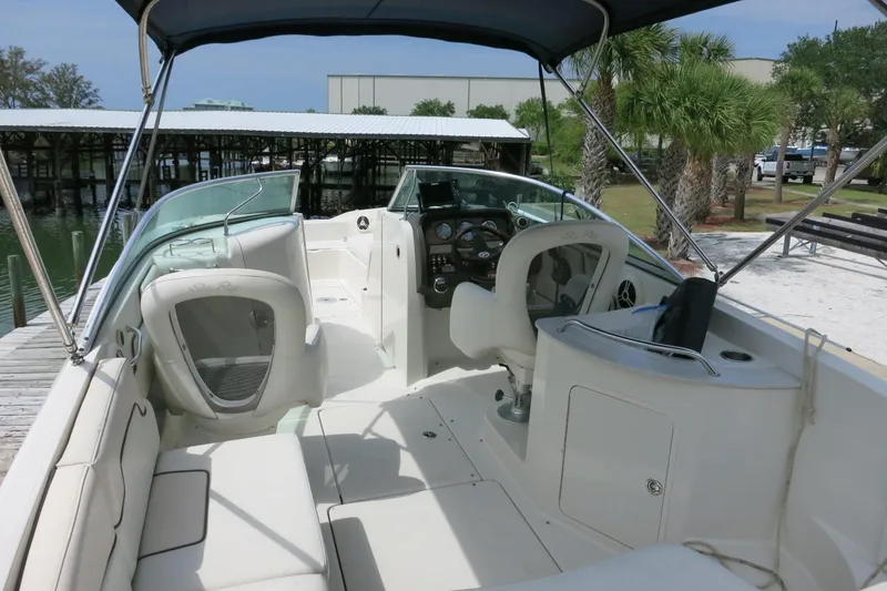 Slide: The Image of 2008 Sea Ray 260 Sundeck boat interior with seating and helm, docked near palm trees. - 9