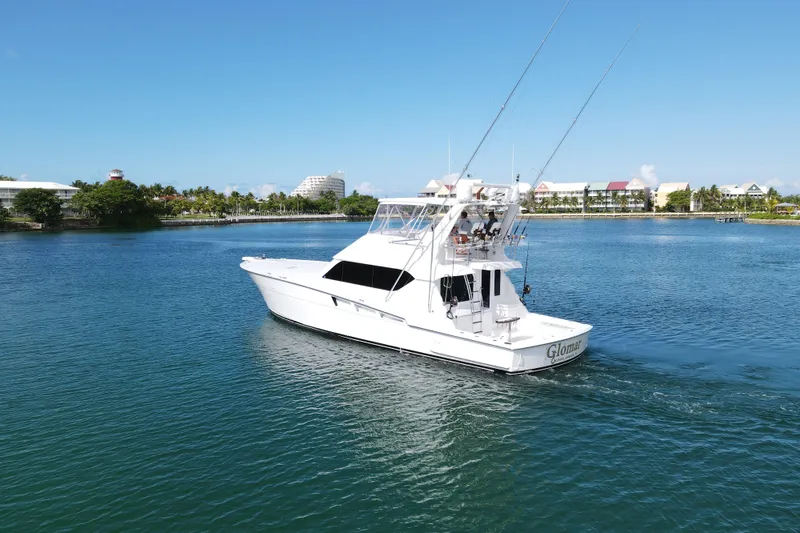 Slide: The Image of 2004 Hatteras 60 Convertible yacht cruising in a scenic coastal area. - 10