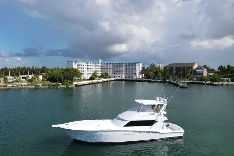 Slide: The Image of 2004 Hatteras 60 Convertible yacht cruising near waterfront buildings under cloudy skies. - 11