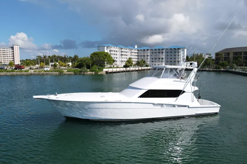 Slide: The Image of 2004 Hatteras 60 Convertible yacht on calm water with buildings in the background. - 12