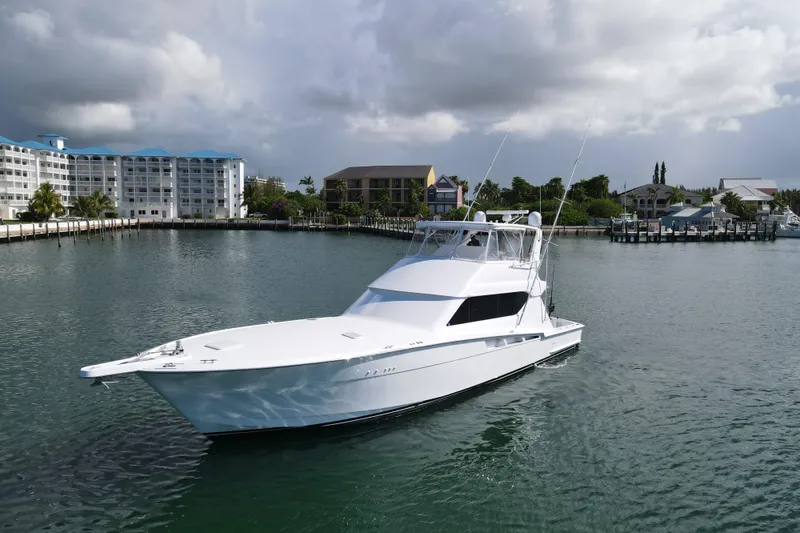 Slide: The Image of 2004 Hatteras 60 Convertible yacht in a serene marina setting. - 13