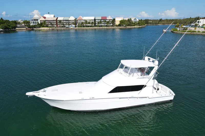 Slide: The Image of 2004 Hatteras 60 Convertible yacht on calm water with scenic background. - 14
