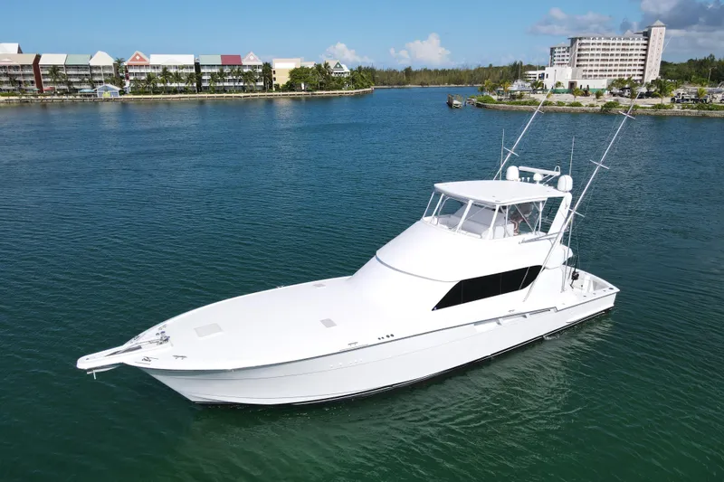 Slide: The Image of 2004 Hatteras 60 Convertible yacht on calm water, with buildings in the background. - 16