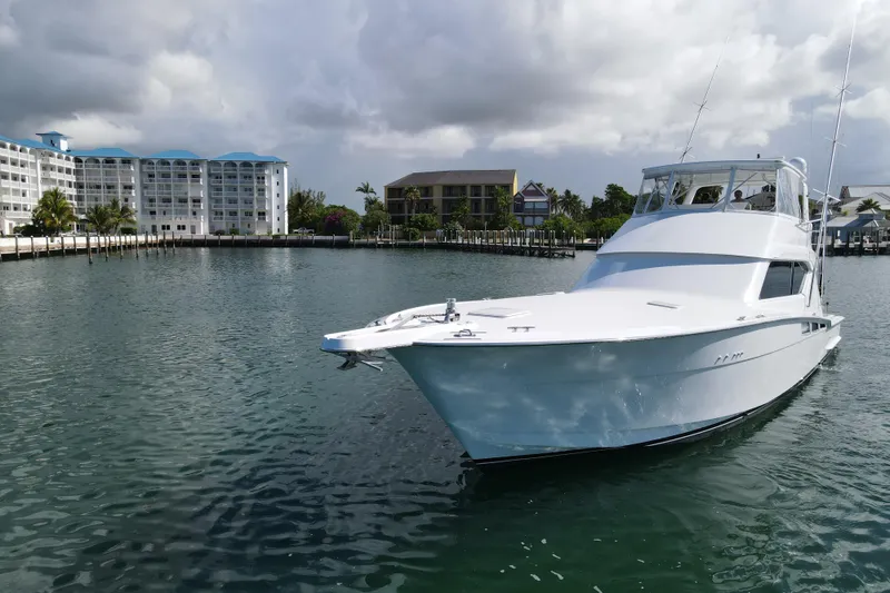 Slide: The Image of 2004 Hatteras 60 Convertible yacht docked near waterfront buildings under cloudy sky. - 21