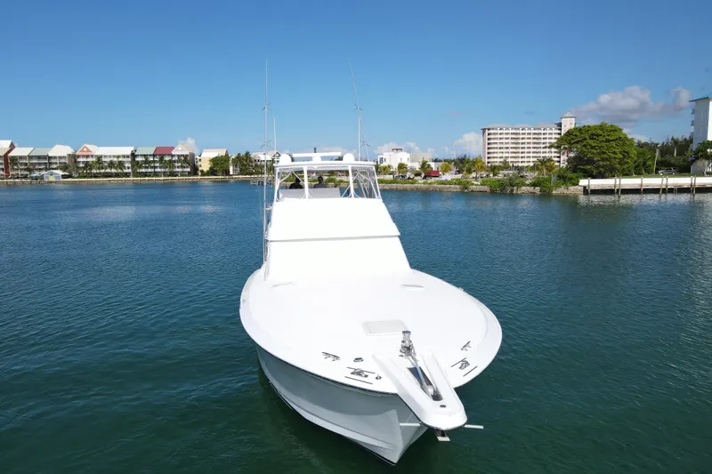 Slide: The Image of 2004 Hatteras 60 Convertible yacht on calm water with coastal buildings in the background. - 23