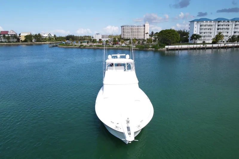 Slide: The Image of 2004 Hatteras 60 Convertible yacht on calm water near coastal buildings. - 24