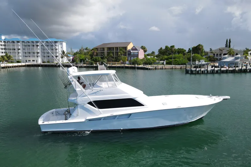 Slide: The Image of 2004 Hatteras 60 Convertible yacht on calm water near coastal buildings. - 25
