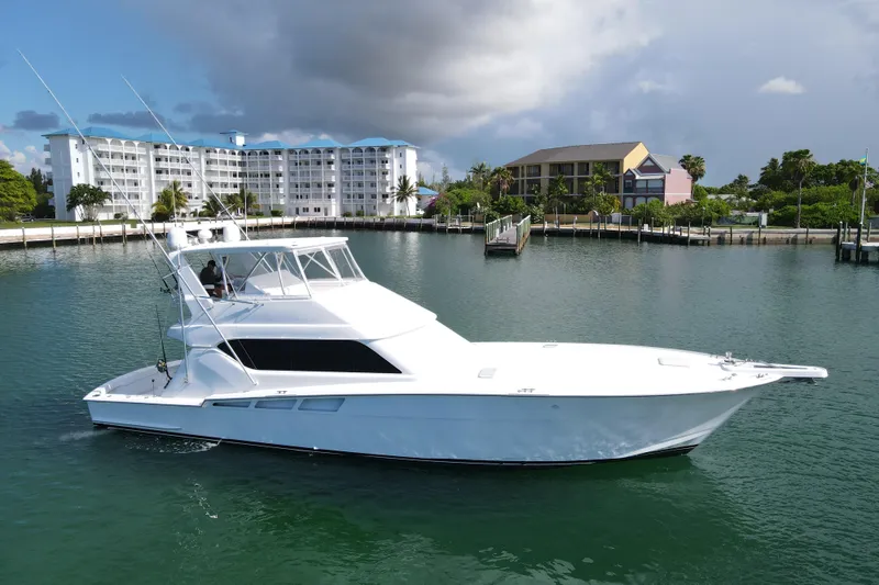 Slide: The Image of 2004 Hatteras 60 Convertible yacht cruising in a marina with waterfront buildings. - 26
