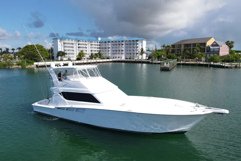 Slide: The Image of 2004 Hatteras 60 Convertible yacht docked near waterfront buildings under cloudy sky. - 27