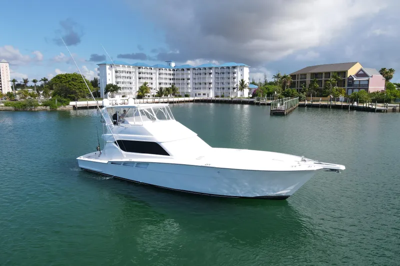Slide: The Image of 2004 Hatteras 60 Convertible yacht on calm water near coastal buildings. - 29