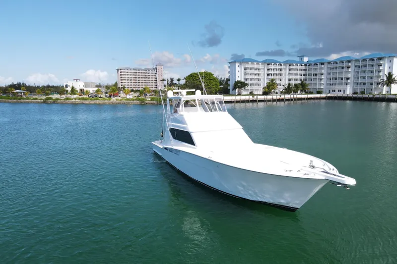 Slide: The Image of 2004 Hatteras 60 Convertible yacht on calm water near coastal buildings. - 30