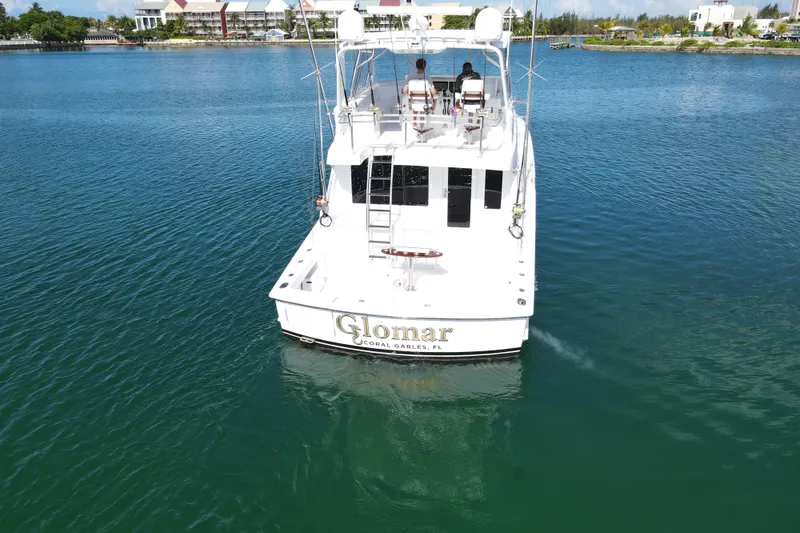 Slide: The Image of 2004 Hatteras 60 Convertible yacht on calm water, rear view, with two people seated. - 33