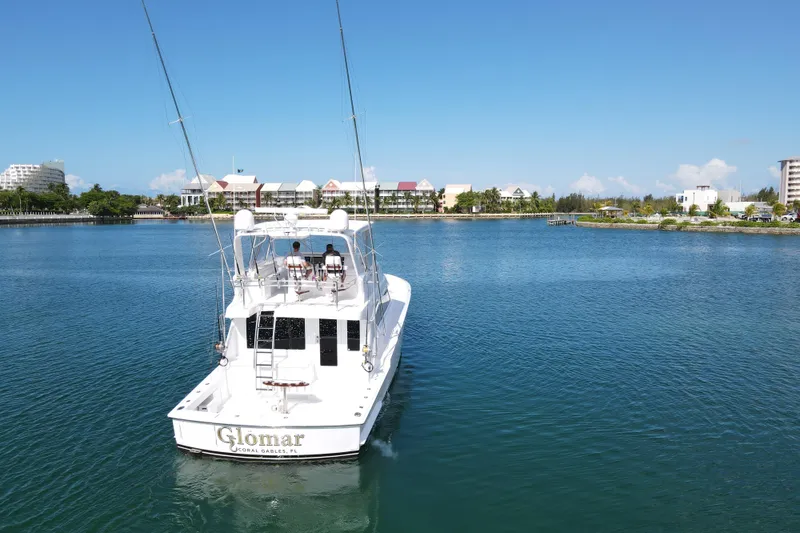Slide: The Image of 2004 Hatteras 60 Convertible yacht cruising in a scenic marina under clear blue skies. - 38