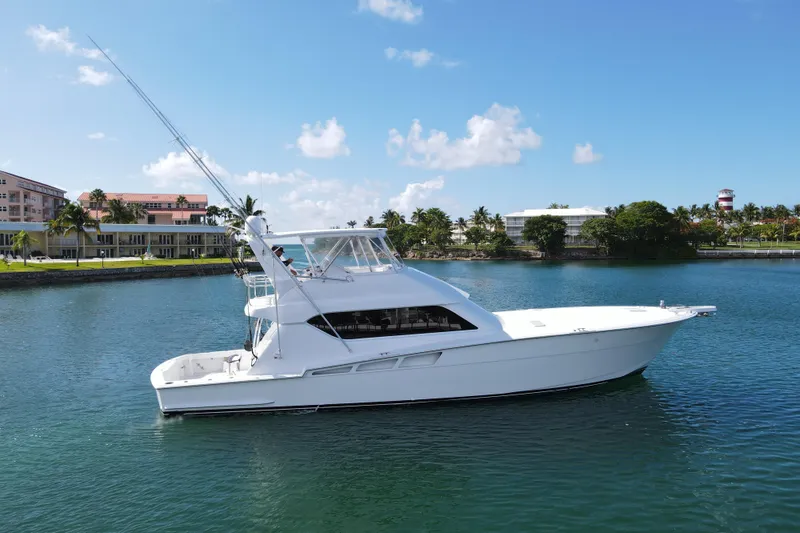 Slide: The Image of 2004 Hatteras 60 Convertible yacht cruising on a sunny day near a coastal resort. - 4