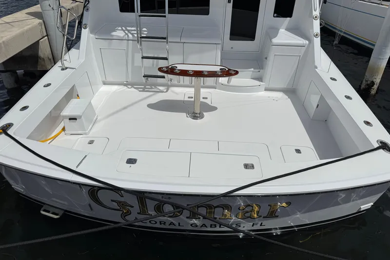 Slide: The Image of 2004 Hatteras 60 Convertible yacht docked, featuring spacious deck and fishing chair. - 41
