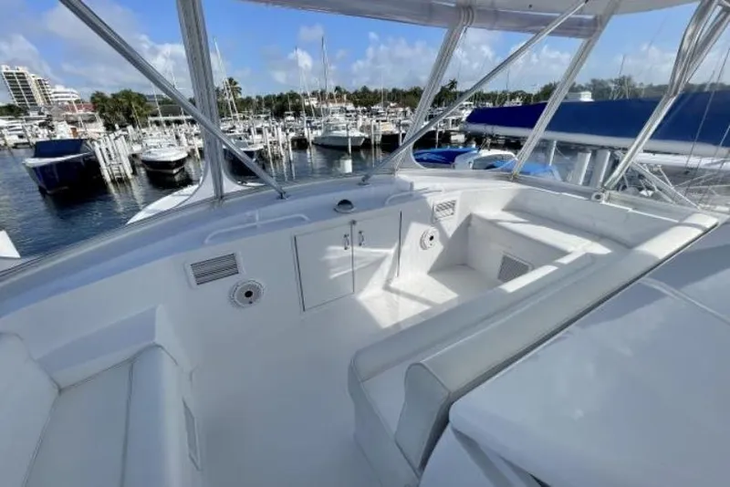 Slide: The Image of 2004 Hatteras 60 Convertible yacht interior with marina view, featuring white seating and cabinetry. - 43