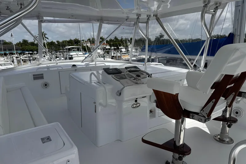 Slide: The Image of Helm of 2004 Hatteras 60 Convertible yacht with white seating and marina view. - 46