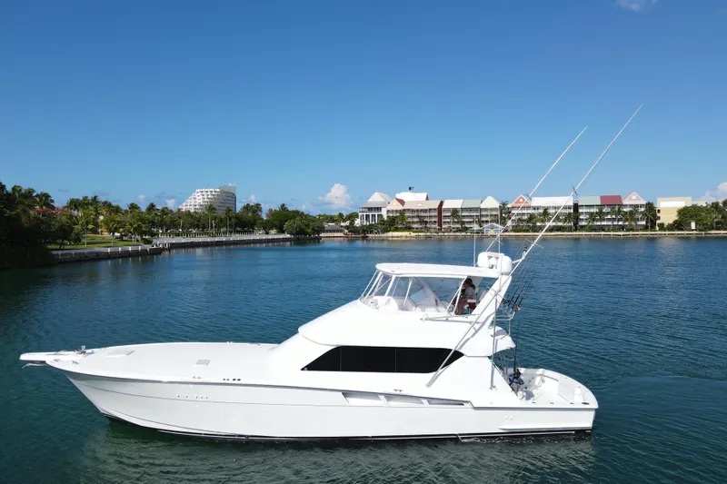 Slide: The Image of 2004 Hatteras 60 Convertible yacht cruising on a sunny day near waterfront buildings. - 5