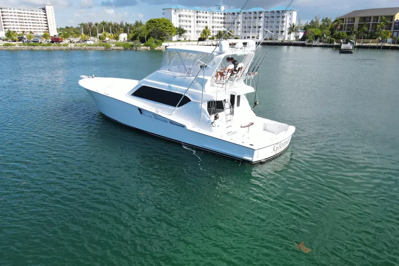 Slide: The Image of 2004 Hatteras 60 Convertible yacht on calm water near coastal buildings. - 9