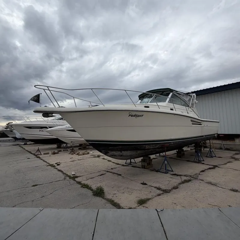 The Image of 1998 Pursuit 3400 Express boat elevated outside warehouse. - 0