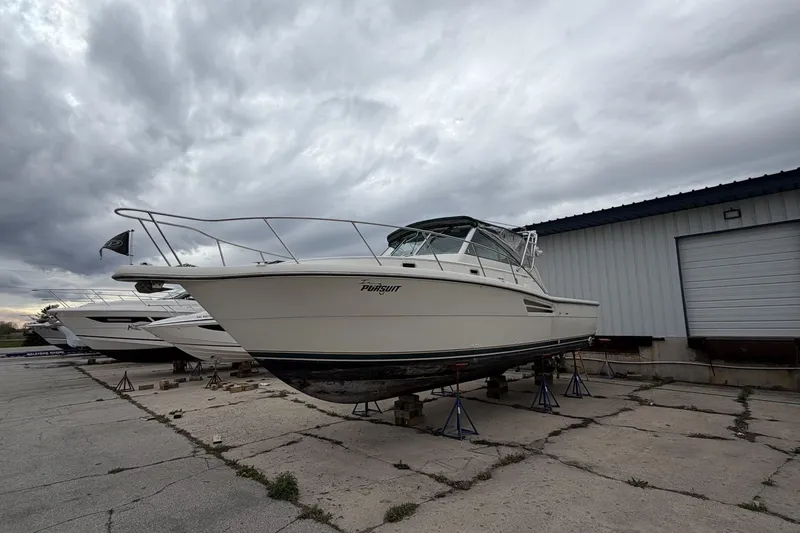 The Image of 1998 Pursuit 3400 Express boat elevated outside warehouse. - 1