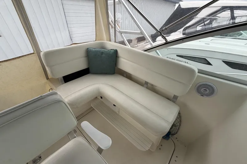 Slide: The Image of Interior of a 1998 Pursuit 3400 Express boat with white seating and a teal cushion. - 16