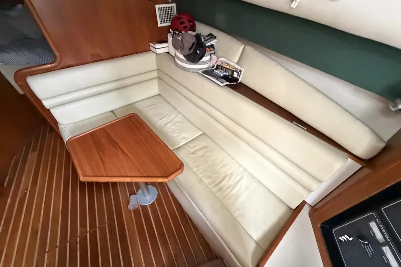 Slide: The Image of Interior of a 1998 Pursuit 3400 Express boat with cream seating and wooden table. - 19