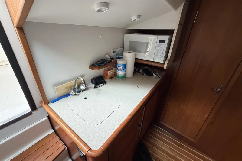 Slide: The Image of 1998 Pursuit 3400 Express boat interior with kitchenette, microwave, and wooden cabinetry. - 21