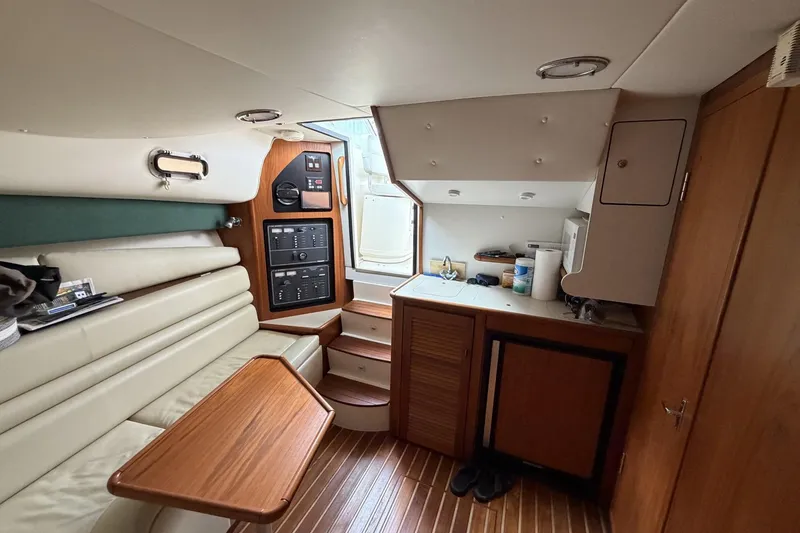 Slide: The Image of Interior of a 1998 Pursuit 3400 Express boat, featuring a compact kitchen and seating area. - 22